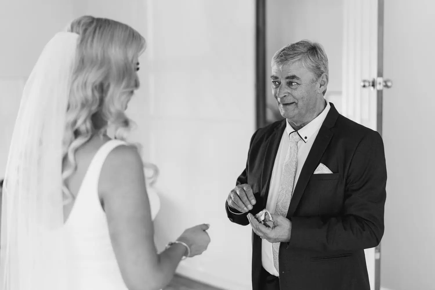 Black-and-white photograph of the bride smiling with an older man indoors