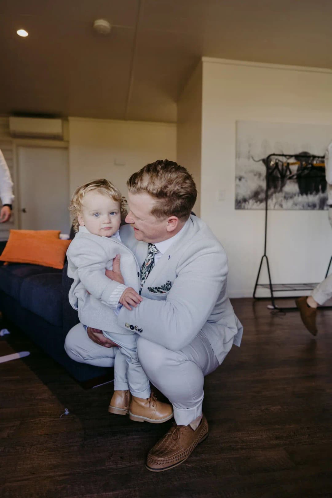 Groom holding a small child while getting ready indoors