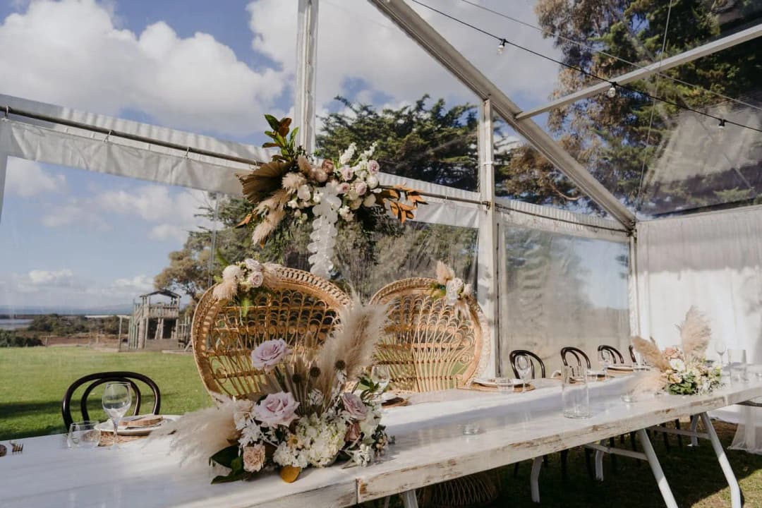 Wicker chairs and a floral arrangement beneath the marquee roof