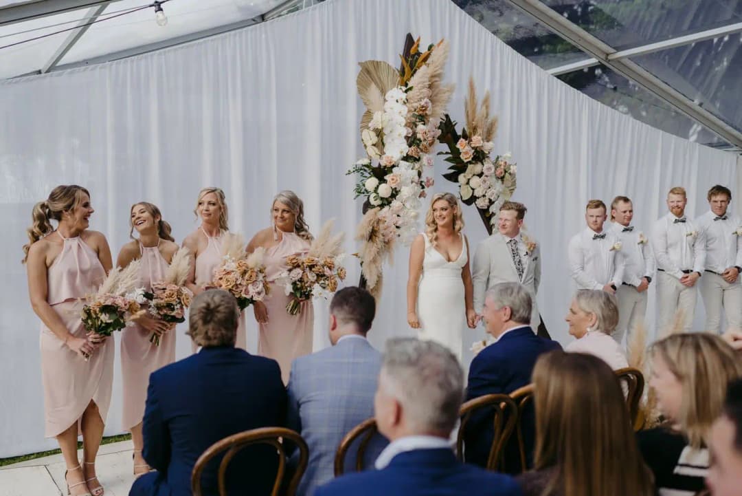 Bride and groom standing before their wedding guests inside the marquee