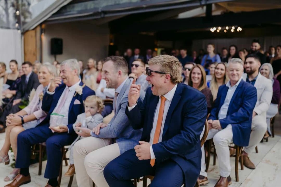 Guests laughing while seated in rows during the ceremony