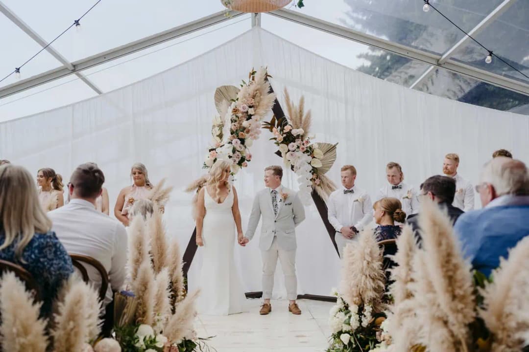 Bride and groom facing each other beneath the floral arch