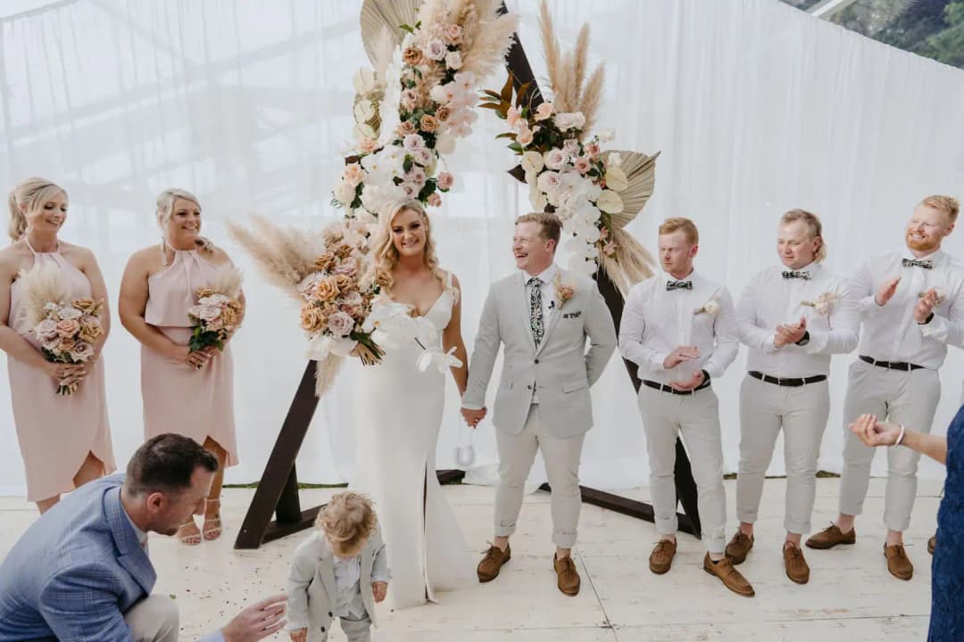 Newlyweds smiling as a small child stands near them after the ceremony