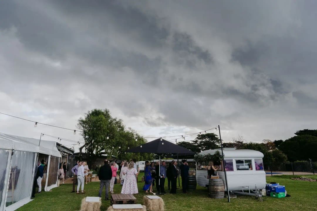 Guests gathering near the bar beneath a cloudy afternoon sky