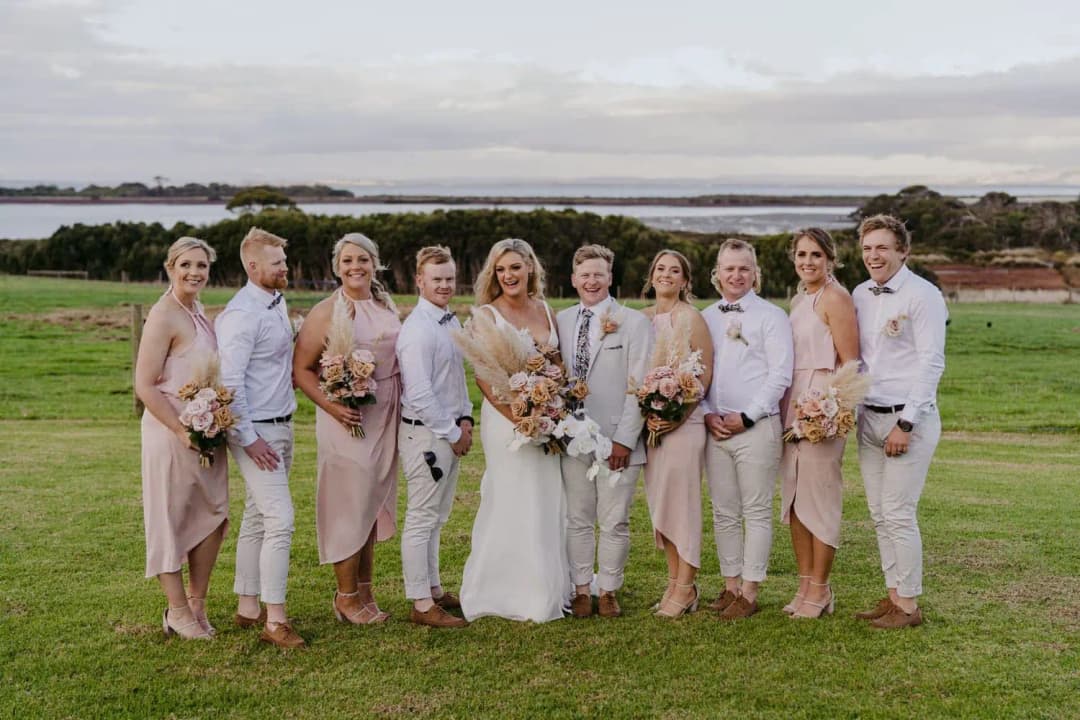 Wedding party standing together on the lawn with bouquets
