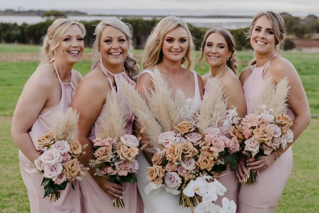 Bride and bridesmaids smiling together with their pastel bouquets