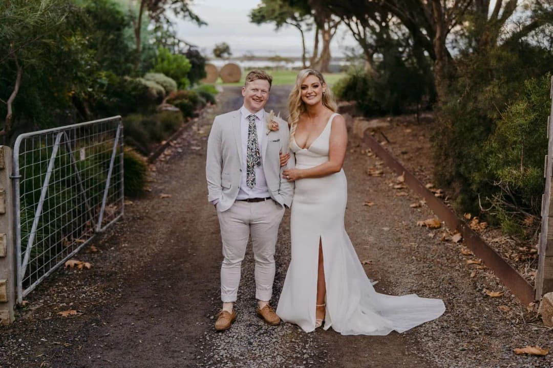 Bride and groom standing together on a tree-lined path
