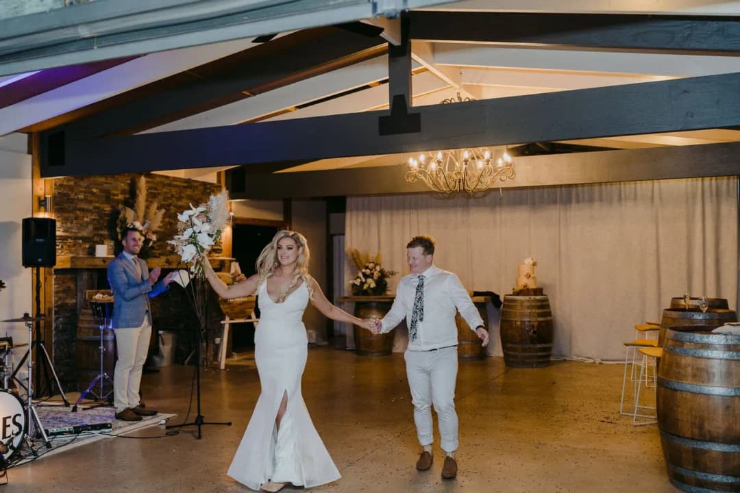 Bride and groom dancing hand in hand across the reception floor