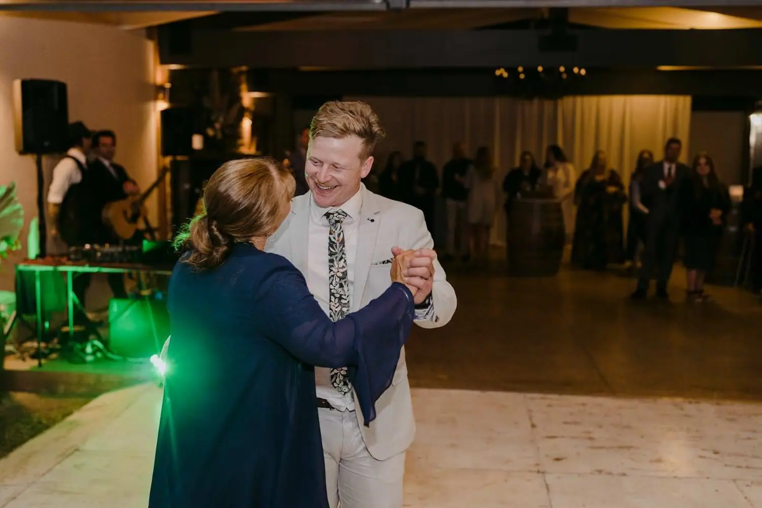Groom dancing with an older guest in a dark blue jacket
