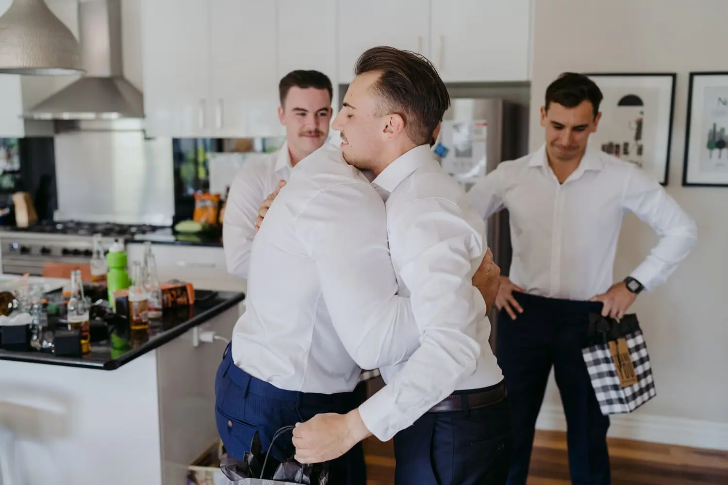 Men in white shirts adjusting their clothing in a kitchen