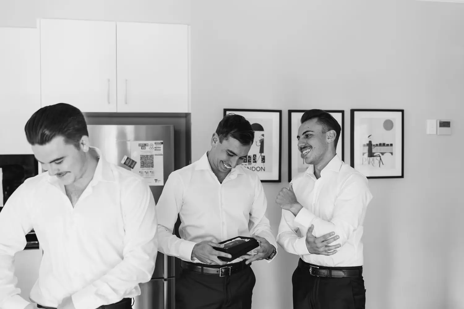 Black and white photograph of men laughing together as they get dressed