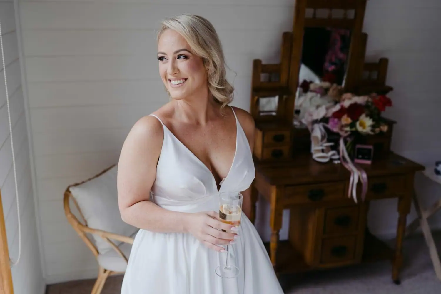 Bride smiling while holding a glass beside a dining table