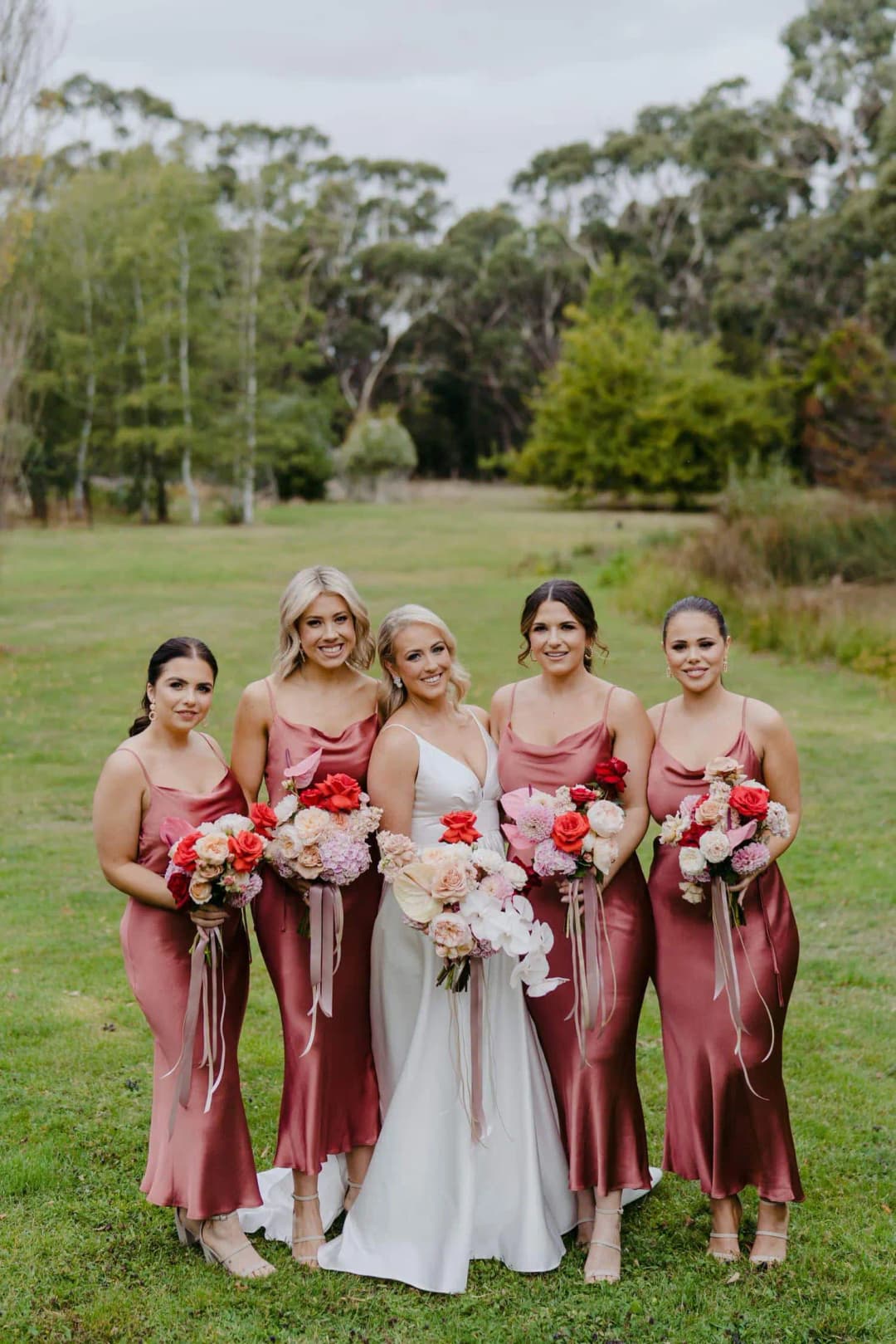 Bride and four bridesmaids standing with bouquets on a lawn