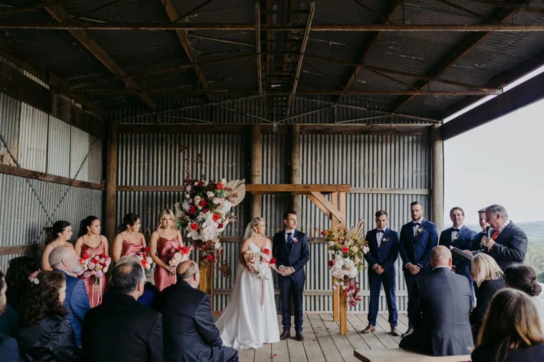 Wedding party gathered beneath the shed roof before seated guests