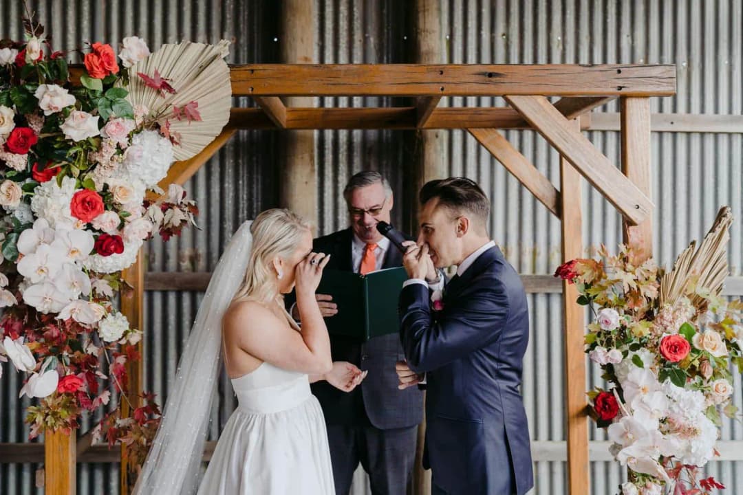 Bride and groom wiping their eyes as the celebrant stands behind them