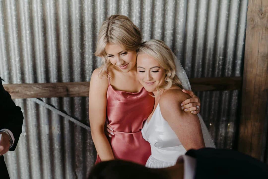 Bride and a bridesmaid smiling together as they look down