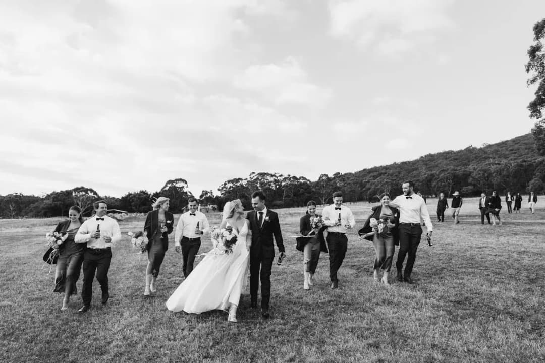 Black and white photograph of the wedding party walking across an open field