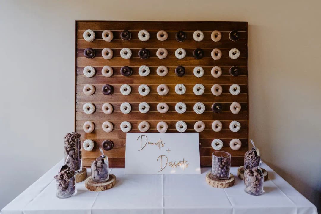 Doughnut wall above a table of small drinks and pastries