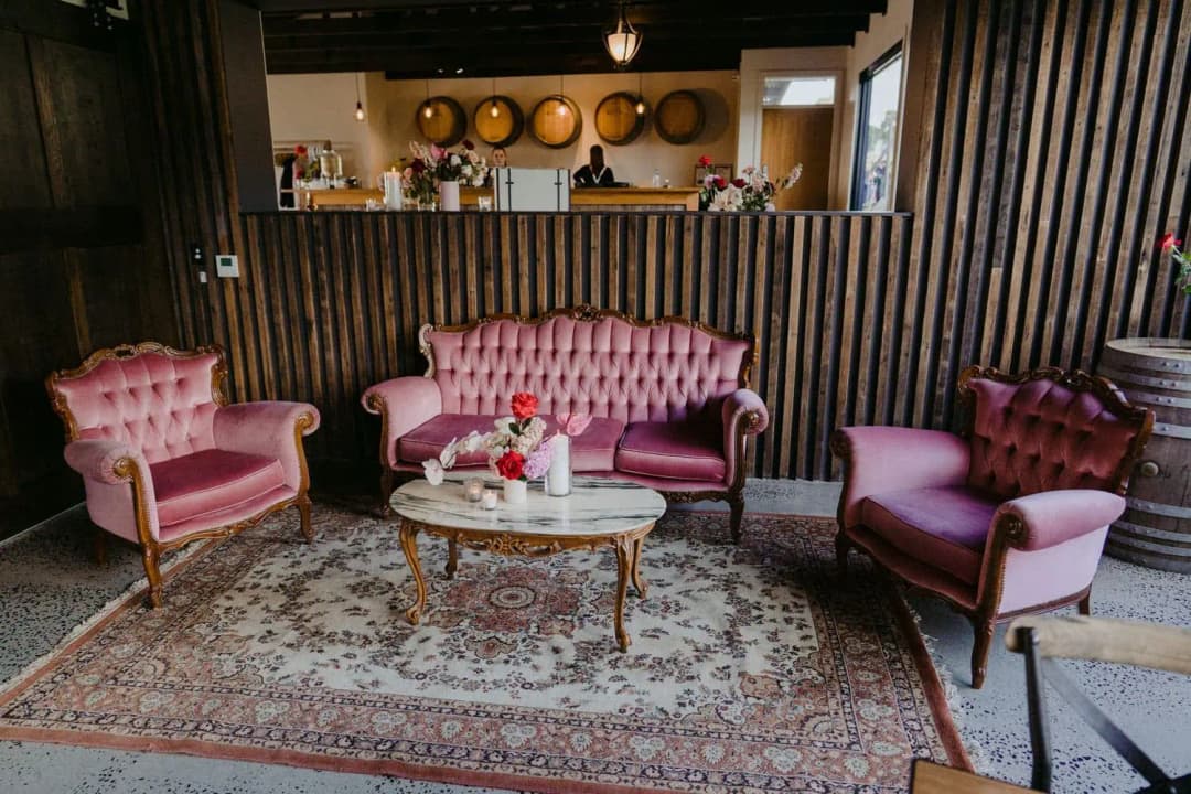 Pink antique-style armchairs and a sofa around a coffee table on a patterned rug