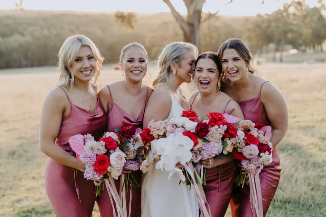 Bride and bridesmaids laughing together with colourful bouquets