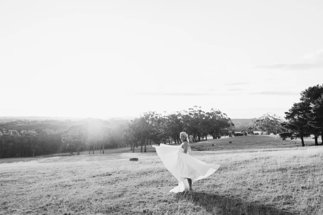 Black and white photograph of the bride twirling her dress in an open field
