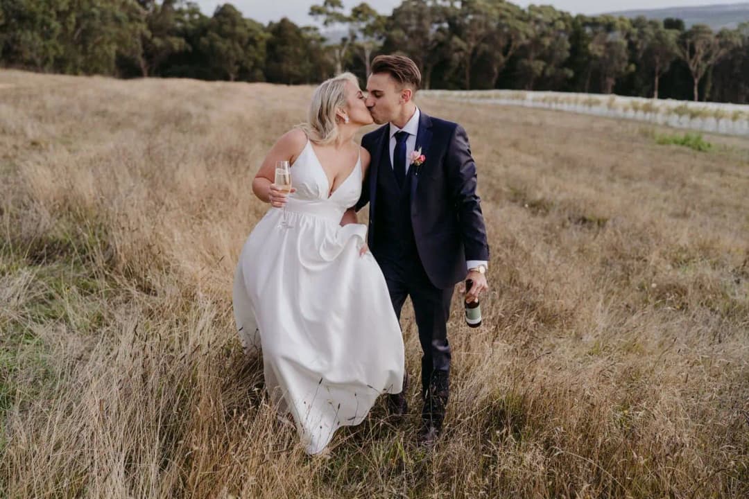 Bride and groom walking together through long grass