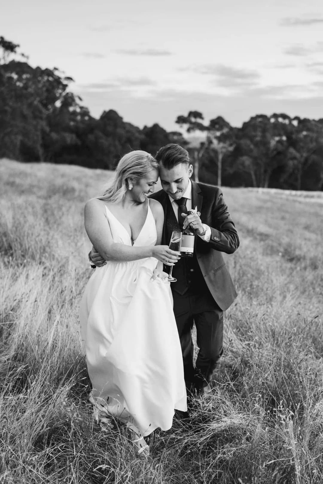 Black and white photograph of the couple walking closely together through a field