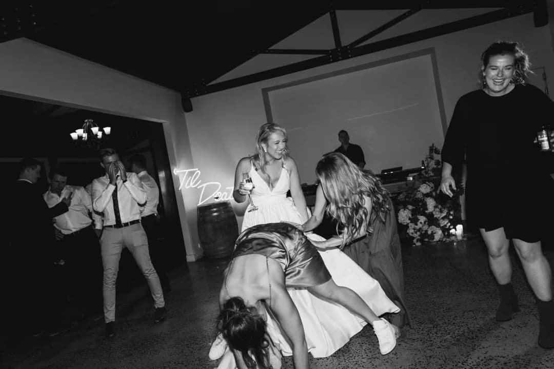 Black and white photograph of guests dancing and laughing at the reception