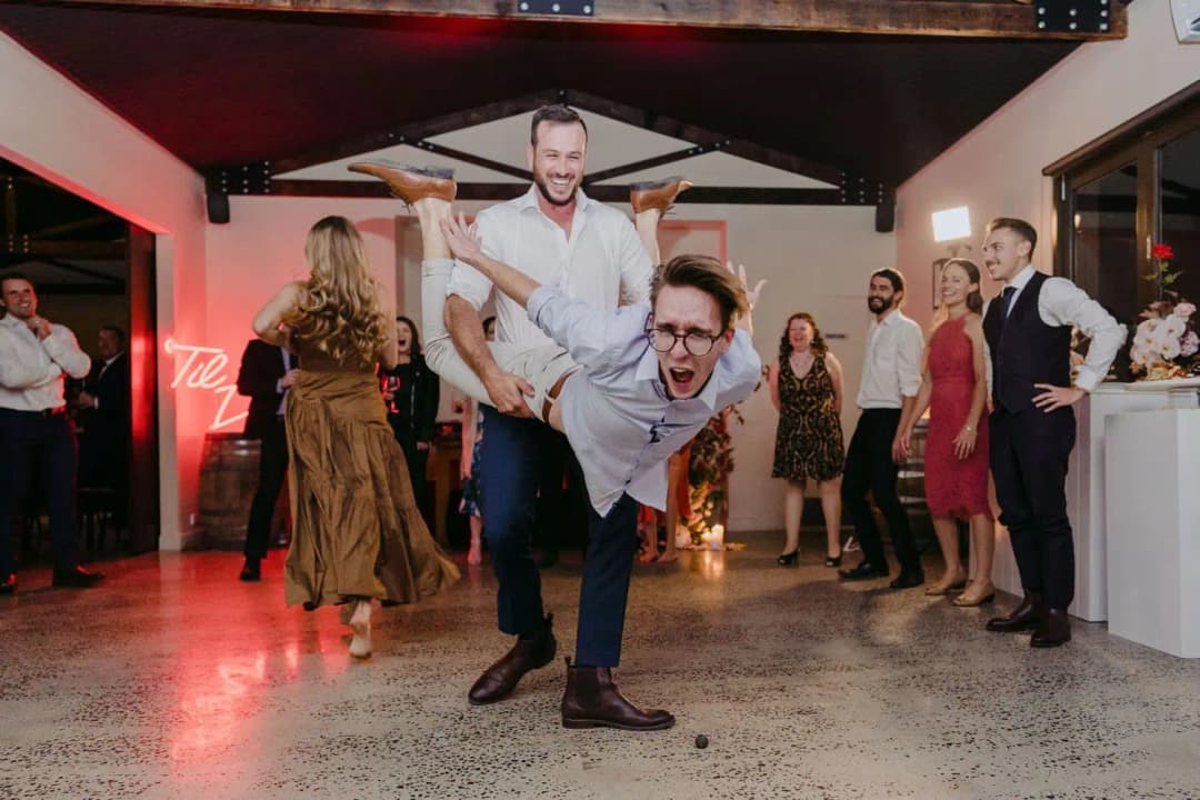 Guest carrying another guest across his back as people laugh around them