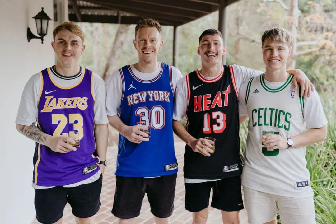 Four men smiling together in colourful basketball jerseys