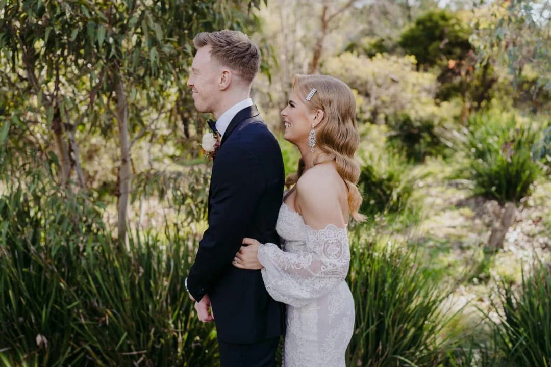 Bride touching the groom’s arm from behind during their first look