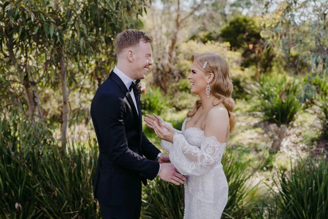 Bride and groom smiling at each other during their first look