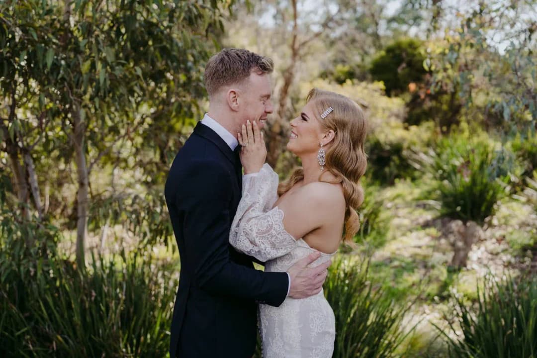 Bride gently touching the groom’s face on a garden path