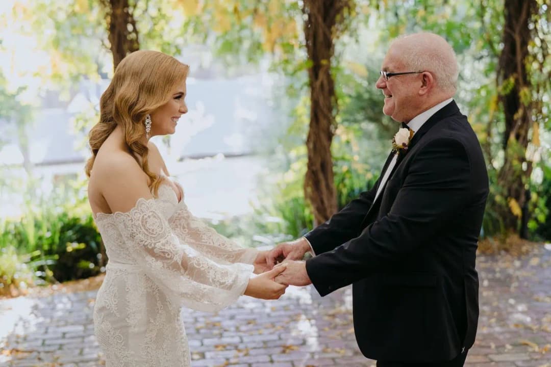 Bride and an older man holding hands and smiling at each other