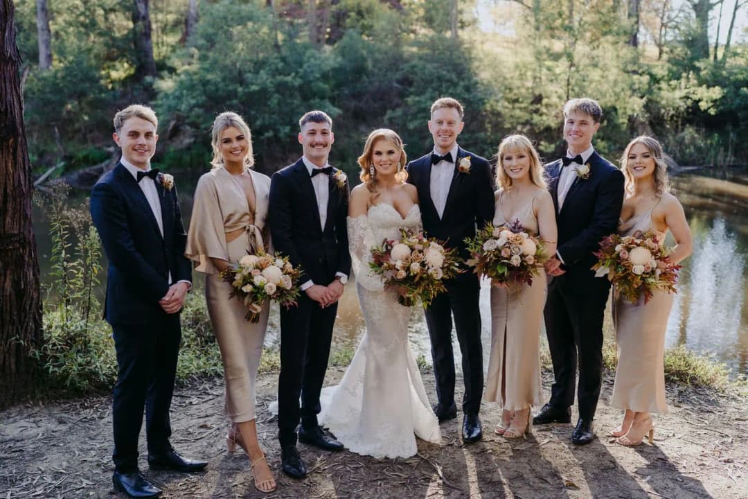 Wedding party standing together on a path surrounded by trees