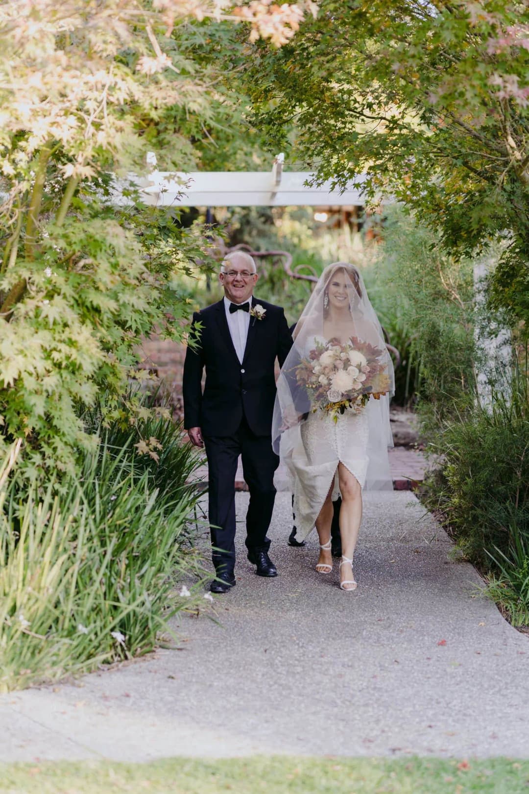 Bride walking beside an older man toward the outdoor ceremony