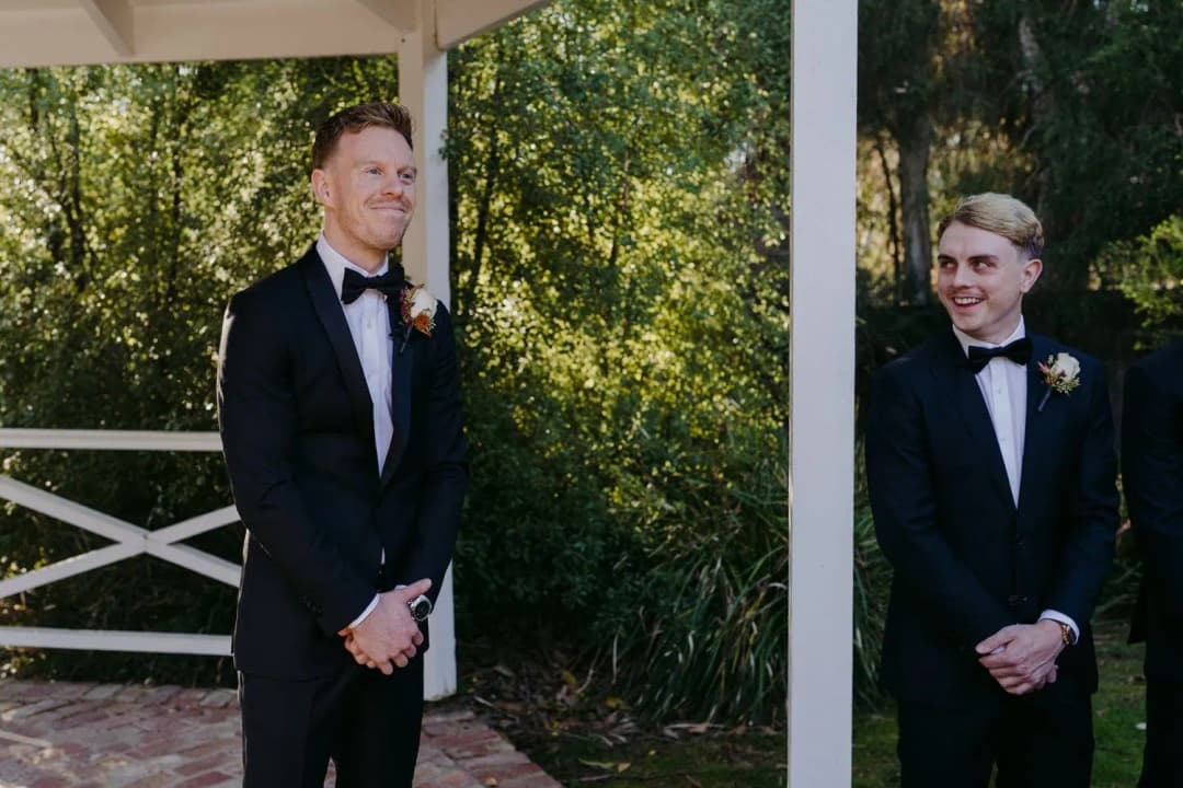 Groom smiling as he waits for the bride with a groomsman behind him