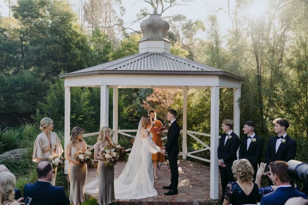 Wedding guests watching the ceremony in a gazebo surrounded by trees