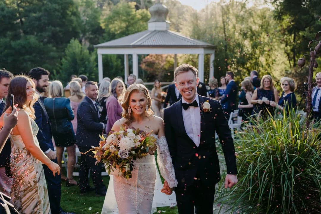 Newlyweds smiling and walking between their wedding guests