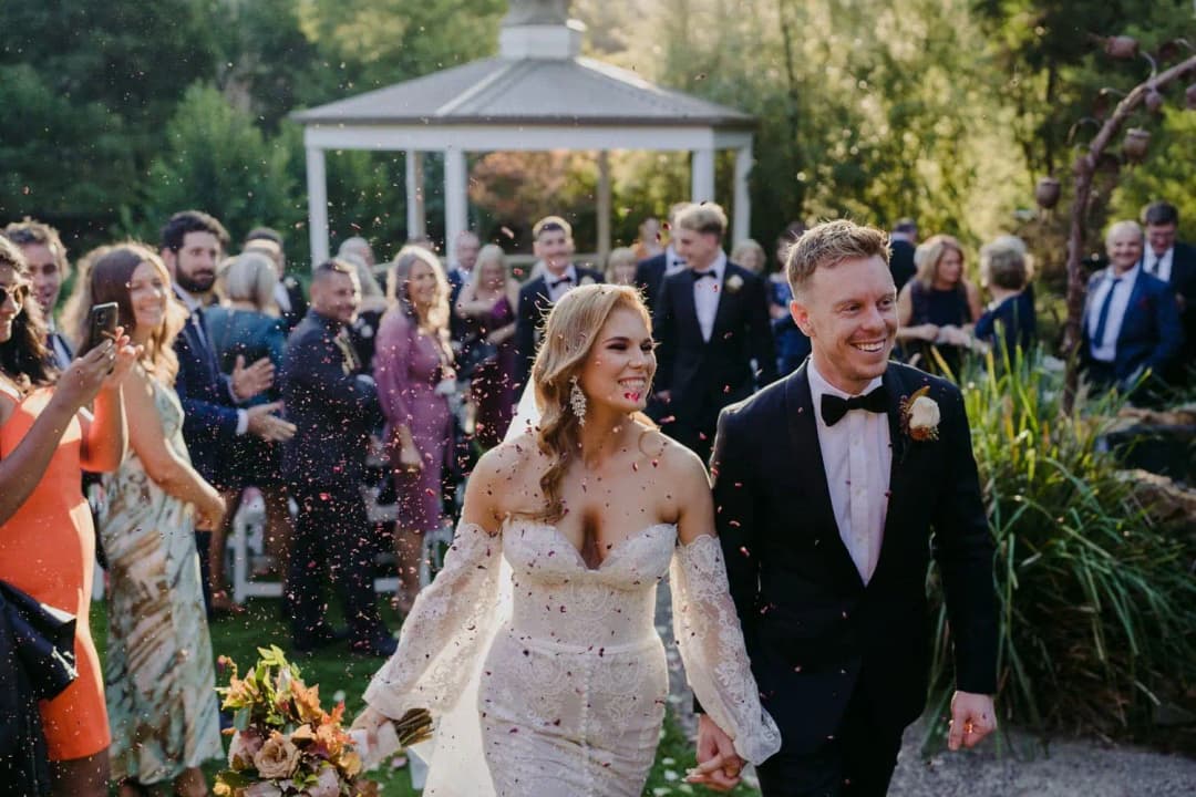 Newlyweds walking beneath falling petals after the ceremony