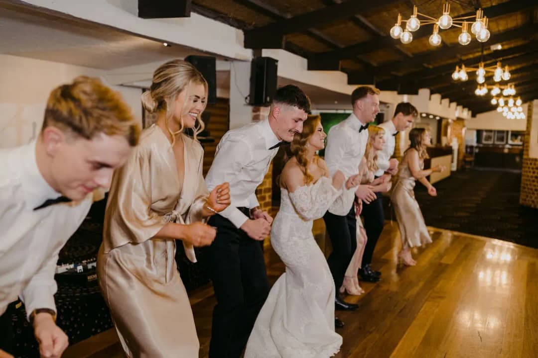 Wedding party laughing and leaning forward together on the dance floor