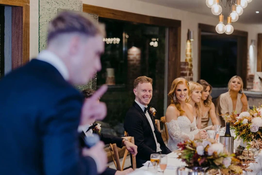 Guests seated at the wedding table laughing during a speech