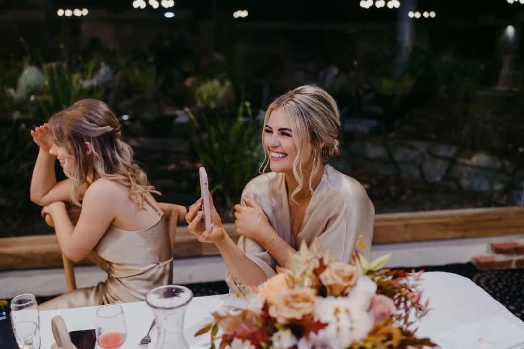 Two bridesmaids smiling while seated beside each other