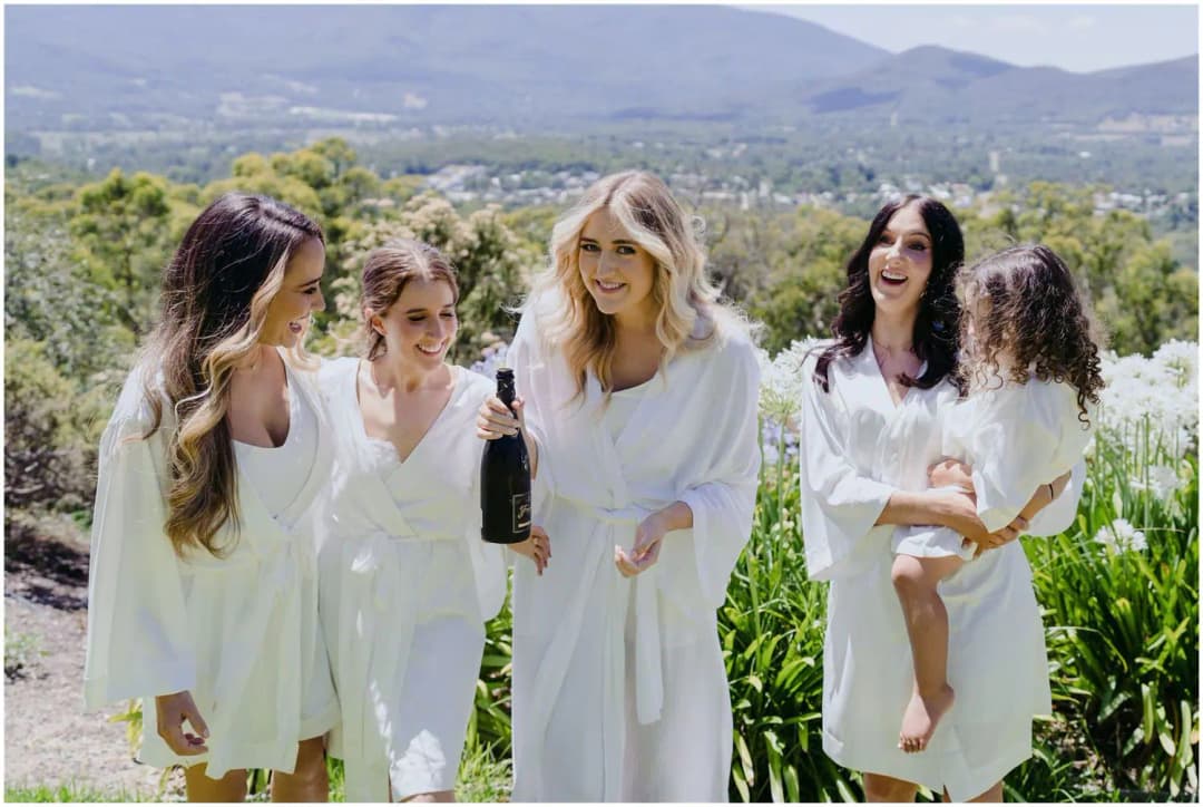 Women and a young child celebrating outdoors with hills in the background