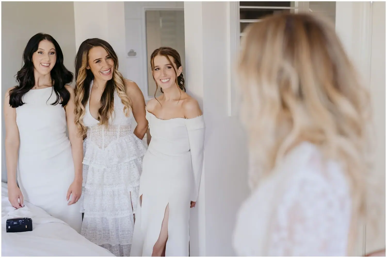 Two photographs of women smiling together indoors in pale outfits