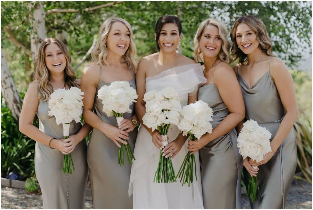 Bride and four bridesmaids smiling together with white bouquets