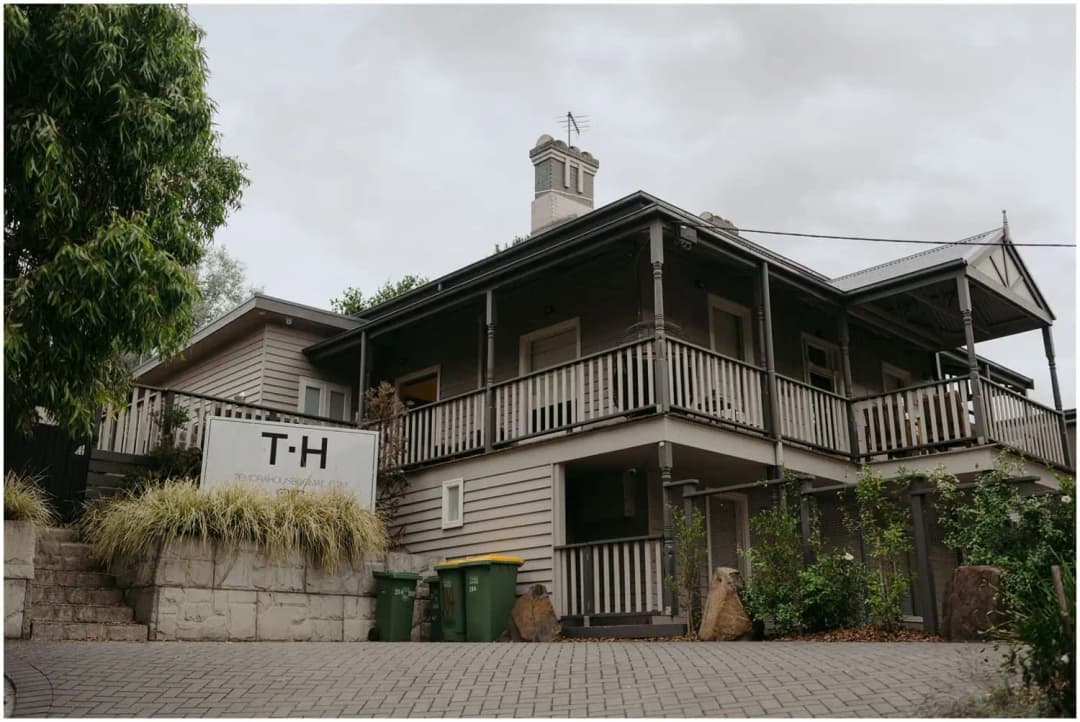Two-storey timber building with wraparound verandas and a T.H sign