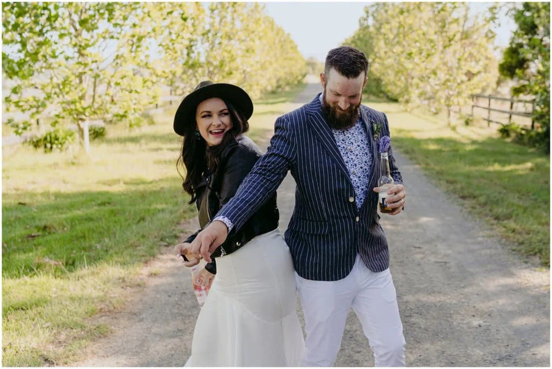 Bride and groom holding hands and turning together on a garden path