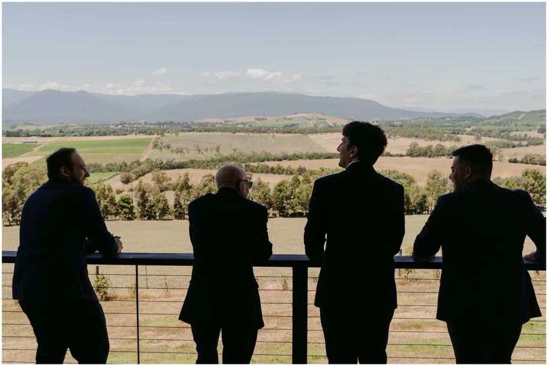 Silhouettes of four men looking across farmland from a balcony