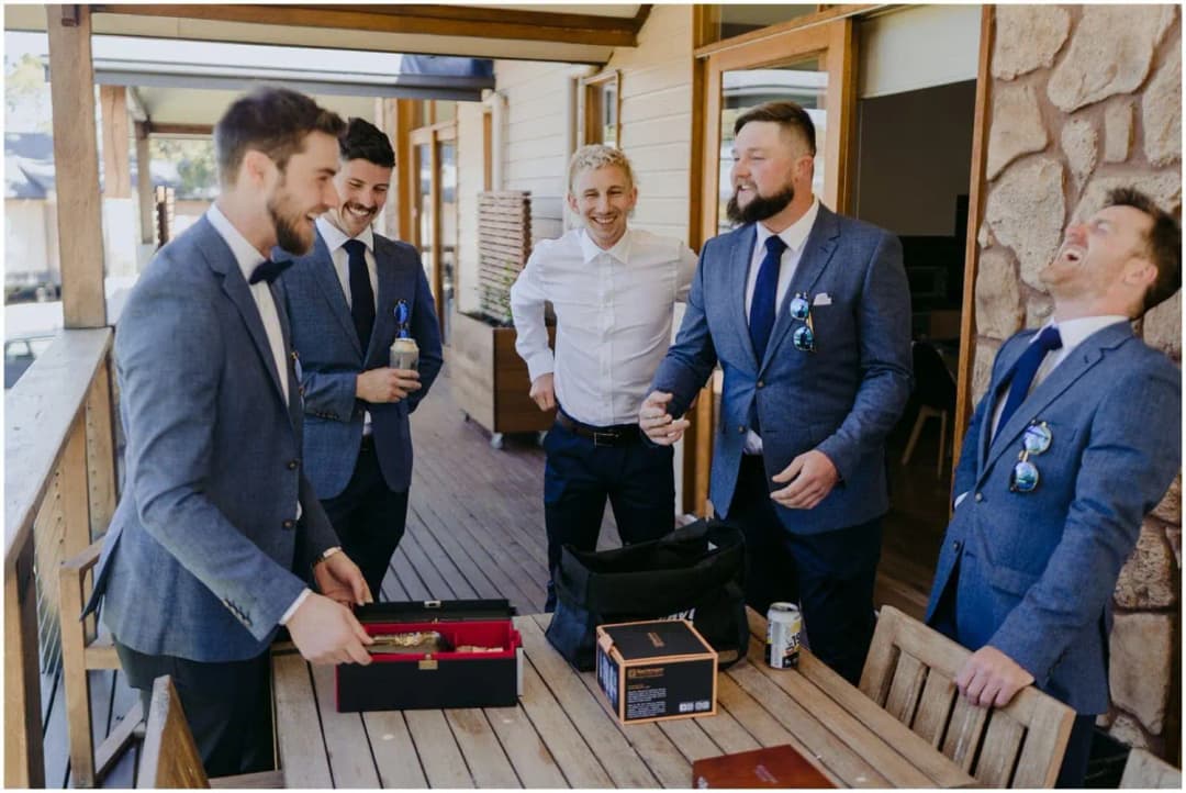 Men laughing together on a veranda beside opened gift boxes